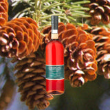 A bottle of Zirbenz Ston Pine Liqueur set against a backdrop of sweet young red pinecones still on the branch.