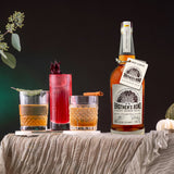 Bottle of Brother’s Bond Straight Bourbon Whiskey on a table next to 3 cocktails.