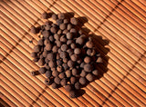 Dark brown peppercorns on a wooden surface