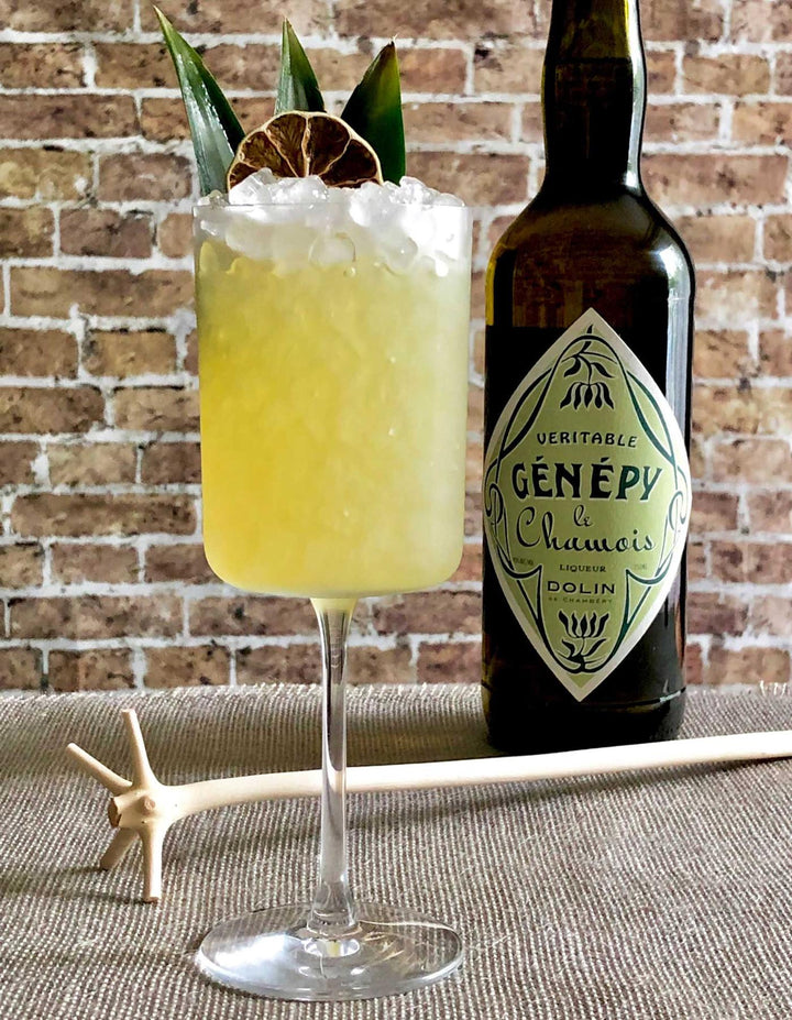 Cocktail with a bottle of Genepy liqueur against a brick wall background
