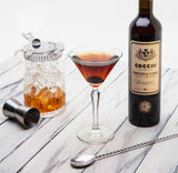Cocchi Vermouth bottle with a cocktail glass and ingredients on a wooden surface