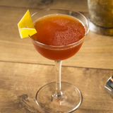 Paper Plane cocktail, in a thin stemmed glass on a wooden table.