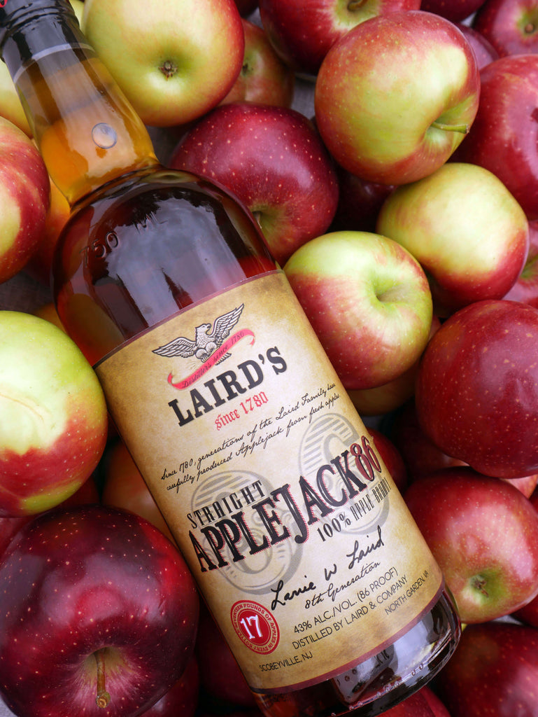 Bottle of Laird's Straight Applejack 86 resting on a pile of apples.