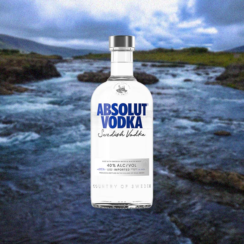 Bottle of Absolut Vodka over backdrop of a river on a cloudy day.