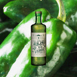 Bottle of Ancho Reyes Verde Chile Poblano Liqueur over blurred background of green chilis