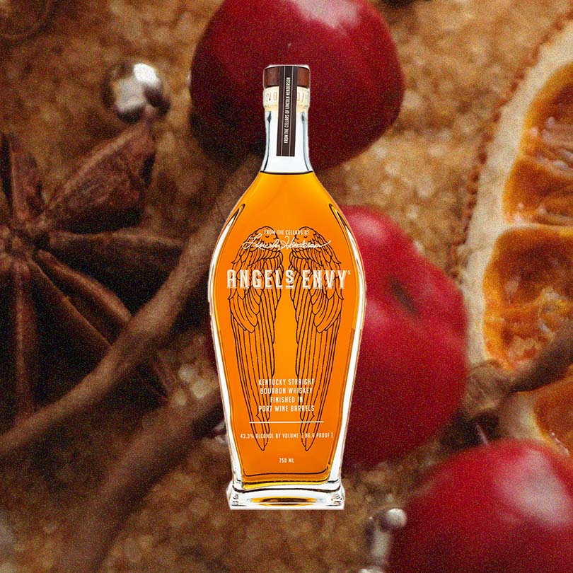Bottle of Angel's Envy Bourbon over blurred background of colorful spices.