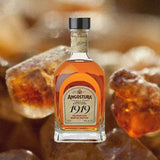 Bottle of Angostura 1919 Rum over backdrop of up close hard orange candies.