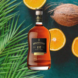 Bottle of Appleton Estate Rare Casks 12 Year Reserve over light blue table with coconut and oranges.