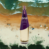 Bottle of Avua Oak Cachaca over background of beach