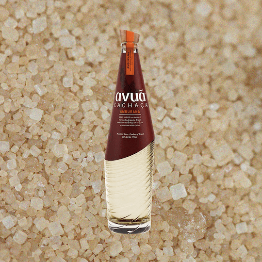 Bottle of Avua Amburana Cachaca over grain, salt, or sand material