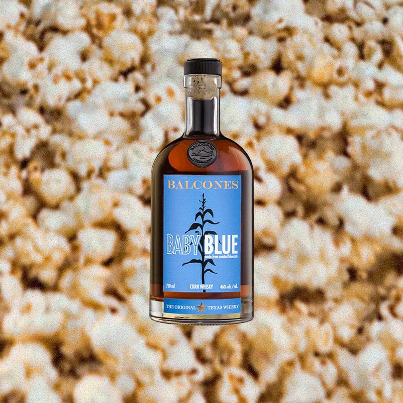 Bottle of Balcones Baby Blue Corn Whisky over backdrop of popcorn.