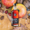 Bottle of Baker's 7 Year Old Single Barrel Bourbon over backdrop of apples and nuts.