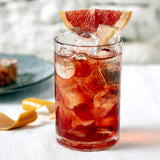 Ruby red cocktail in small glass with grapefruit slice.