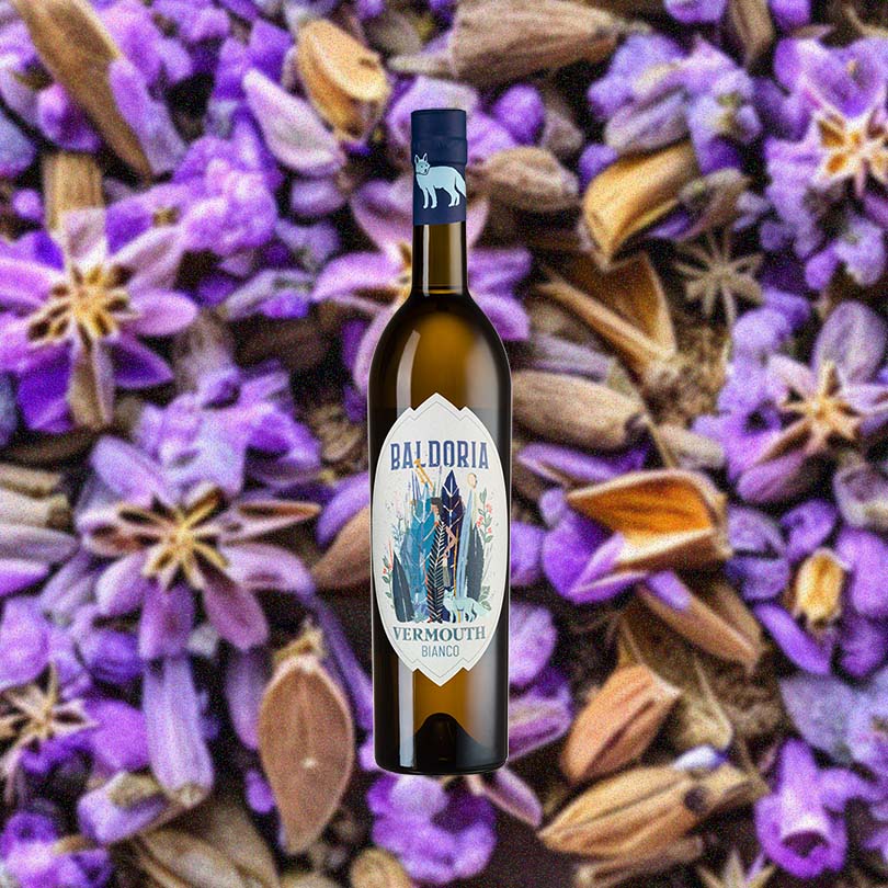 Bottle of Baldoria Bianco Vermouth over background image of purple flowers and herbs.