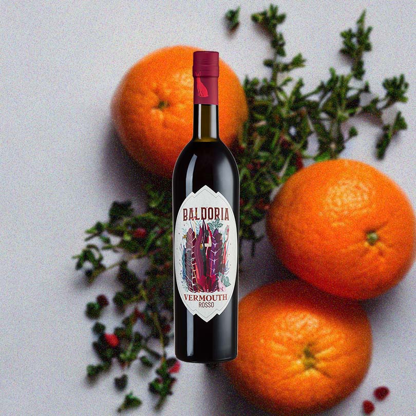 Bottle of Baldoria Rosso Vermouth over backdrop of oranges and greenery.