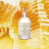 Bottle of Barr Hill Gin over yellow backdrop.