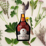 Bottle of Bénédictine Liqueur over backdrop of flowers