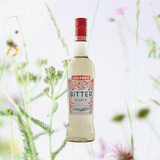 Bottle of Luxardo Bitter Bianco Liqueur over a very light backdrop of sparse flowers