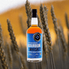 Bottle image of Black Button Four Grain Whiskey over a blurred background image of a field.