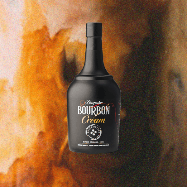 Bottle of Black Button Bourbon Cream over a blurry caramel of flame background