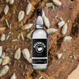 Bottle of Brennivin Aquavit, over close-up background of a grainy loaf of bread.