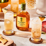 Bottle of Buchanan's Pineapple on a table next to two cocktails.