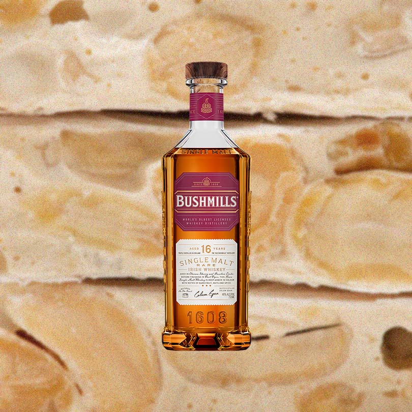 Bottle of Bushmills 16 Year Single Malt Irish Whiskey over backdrop of candy.