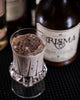 A chocolate, creamy looking cocktail served in a glass with pellet ice. Foursquare Crisma Rum Cream bottle in the background.