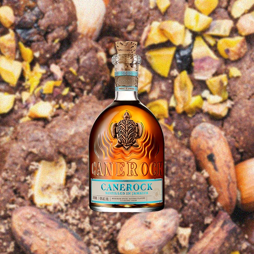 Bottle of Canerock Spiced Rum over back drop of the ground.