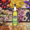 Bottle of Chartreuse Green Liqueur. Backdrop of colorful fruits, seeds and flowers on wooden boards.