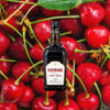 Bottle of Bottle of Heering Cherry Liqueur over backdrop of bright red cherries.