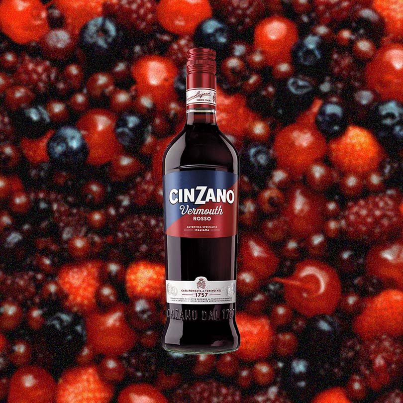 Bottle of Cinzano Rosso Sweet Vermouth over backdrop image of berries.