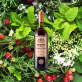 Bottle of Cocchi Vermouth Di Torino over backdrop of mint, berries, and flowers.