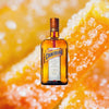 Bottle of Cointreau Liqueur over bright orange backdrop of candies.