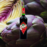 Bottle of Cynar over blurred background of purple artichokes.