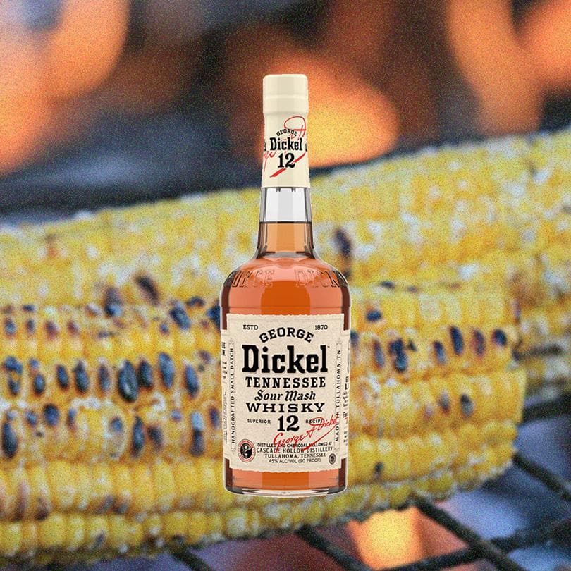 Bottle of George Dickel Superior Recipe No. 12 in front of image of charred corn on the cob on the grill.