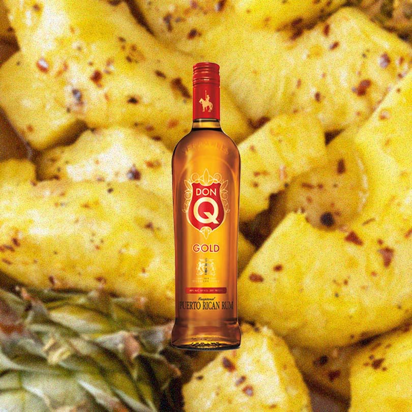Bottle of Don Q Gold Rum over backdrop of pineapple.