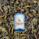 Bottle of Drumshanbo Gunpowder Irish Gin over backdrop of brown leaves or foliage.