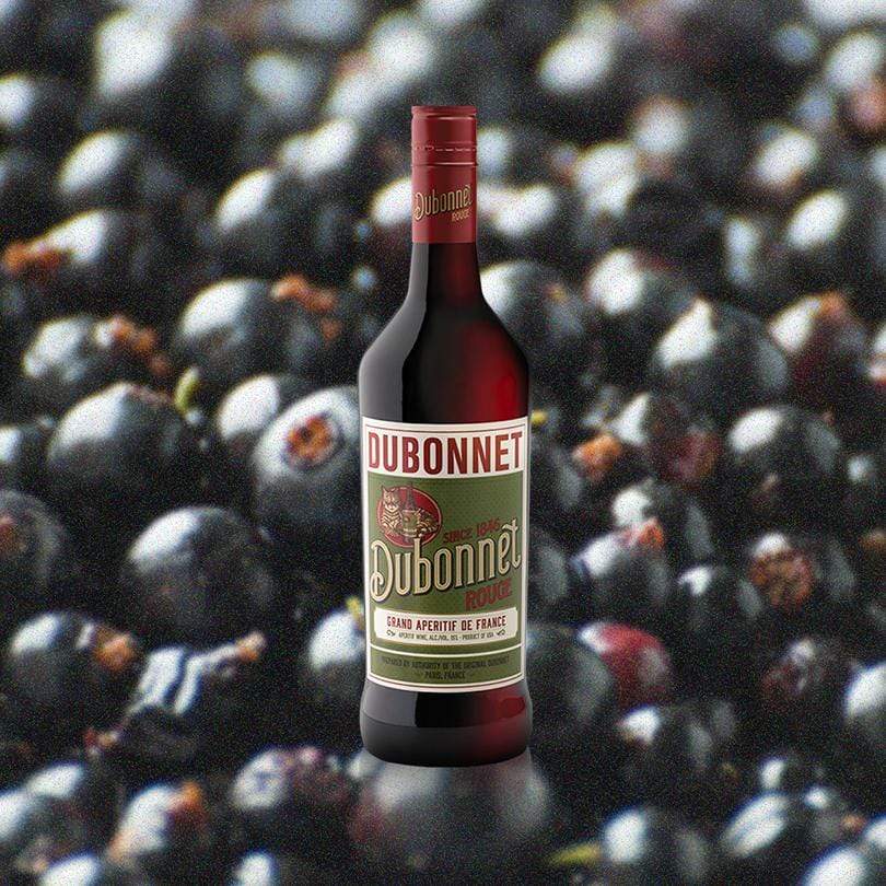 Bottle of Dubonnet Rouge over backdrop of blueberries. 