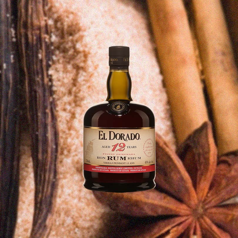 Bottle of Bottle of El Dorado 12 Year Old Rum over backdrop of Cinnamon and spices.