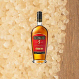 Bottle of El Dorado 5 Year Aged Rum. Backdrop of light colored sugar.