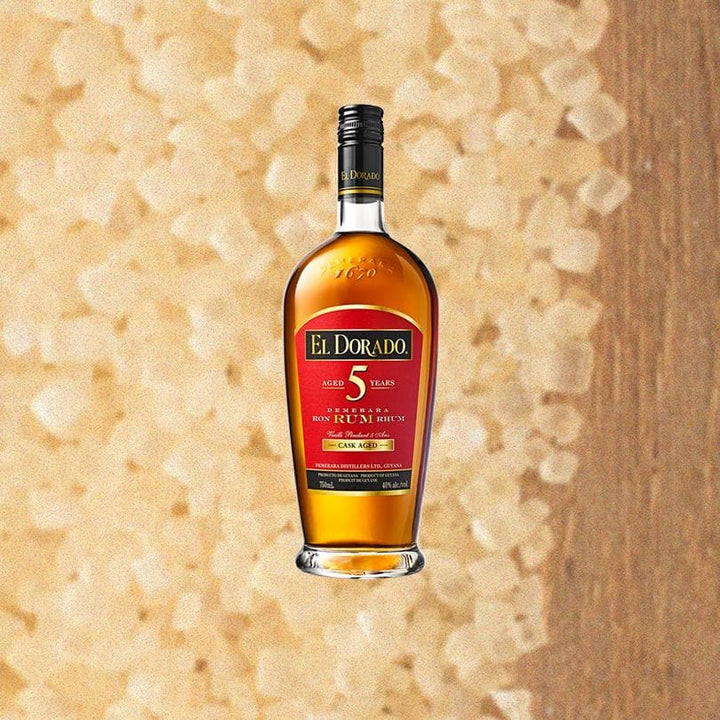 Bottle of El Dorado 5 Year Aged Rum. Backdrop of light colored sugar.