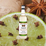 Bottle of John D. Taylor's Velvet Falernum. Backdrop of lime wheel and spices.