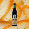 Bottle of Fernet Branca Liqueur on an unidentifiable bright orange background.
