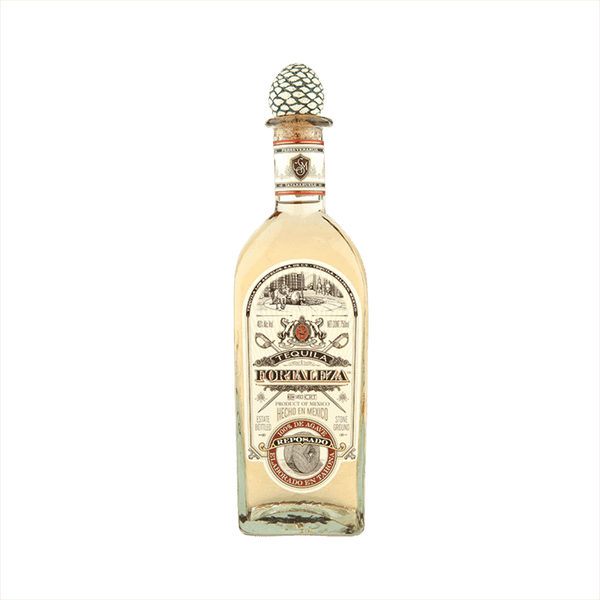 Bottle of Fortaleza Tequila Reposado the label is vintage with red details. The top of the bottle has the signature agave cork topper.