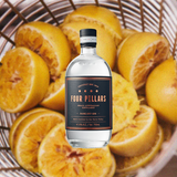 Bottle of Four Pillars Rare Dry Gin, over background of sliced grapefruits in a metal basket.