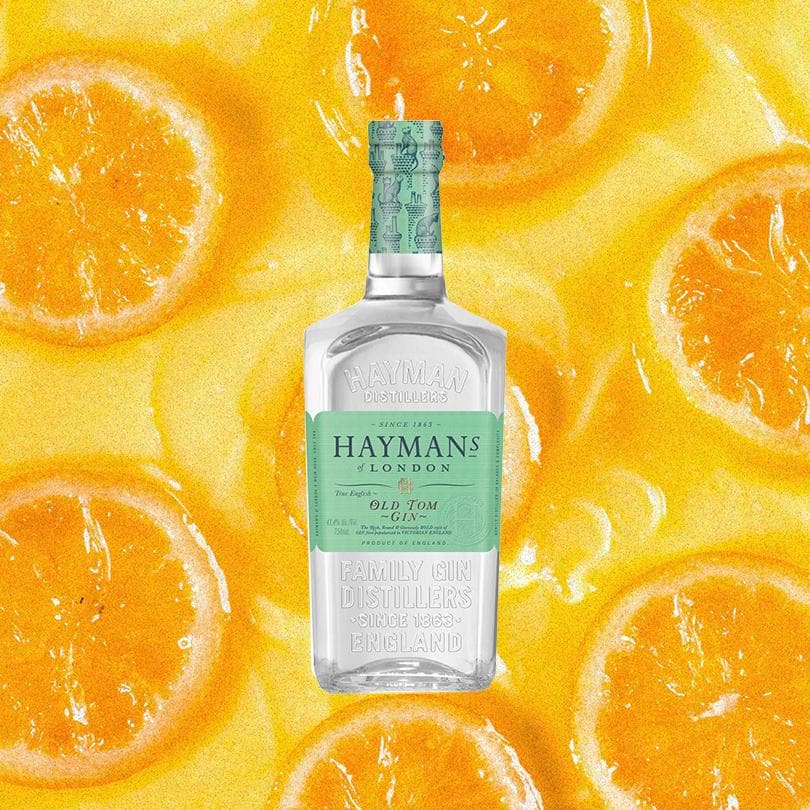 Bottle of Hayman's Old Tom Gin over blurred background of orange fruits.
