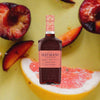 Bottle of Hayman's Sloe Gin, over background of apricot and citrus fruits.