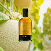 Bottle of  Kikori Japanese Rice Whiskey over backdrop of cantaloupe fruit.