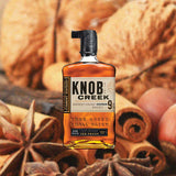 Bottle of Knob Creek 9 Year Old Bourbon Whiskey, over blurred background of nuts and spices.